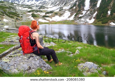Hiker woman seating and resting on shores of mountain lake