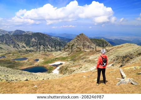 Beautiful mountain landscape with young woman standing and admiring the view