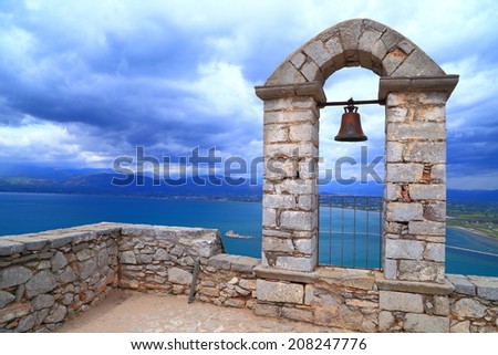 Dark clouds in the sky above sea and the bell tower of Palamidi fortress, Nafplio, Greece