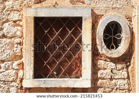 Square and round window with iron bars inside Venetian town of Rovinj, Croatia