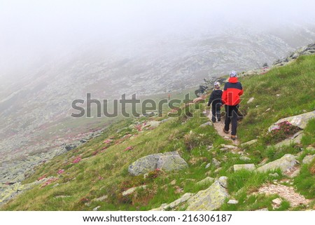 Young mother walking behind small boy on the foggy mountain trail