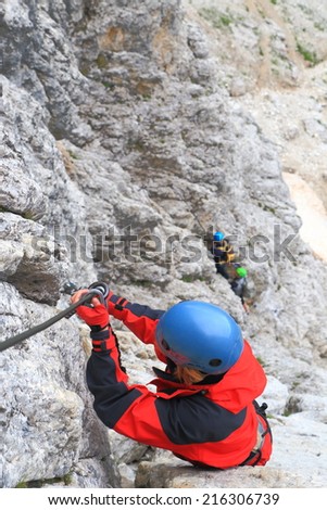 Woman clips the safety gear on the protection cable of via ferrata \