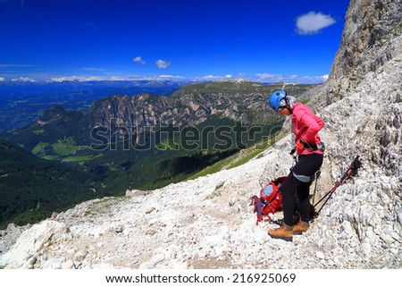 Woman adjusts climbing gear preparing for via ferrata 