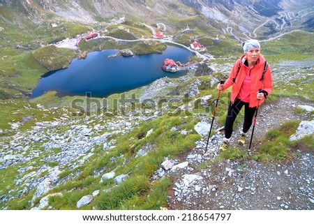 Young hiker on the mountain trail high above glacier lake surrounded by chalets
