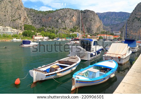 Fishing boats anchored in small harbor surrounded by tall rocks on the Dalmatian coast, Omis,Croatia