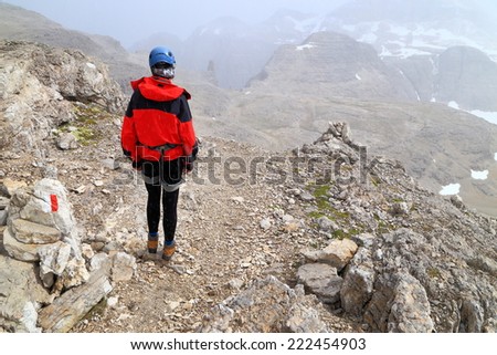 Harsh weather on the Meisules plateau with climber woman walking under snow fall, Sella massif, Dolomite Alps, Italy