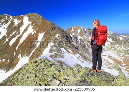 Hiker woman standing on granite boulders surrounded by sunny mountains