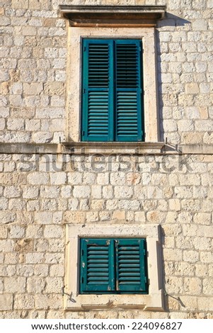 Traditional windows with wood shutters closed on stone facade of Mediterranean house, Dubrovnik, Croatia