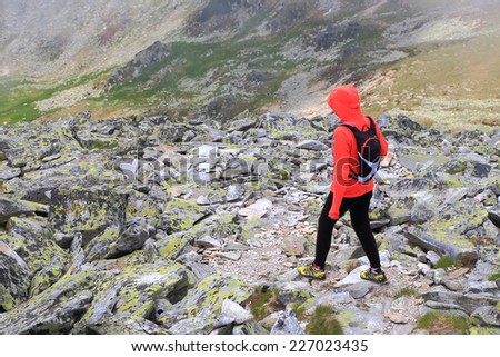 Hiker woman follows a trail amongst large boulders to the valley