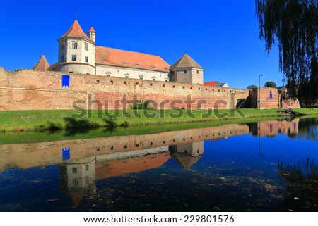 Old castle mirrored by surrounding moat, Transylvania, Romania