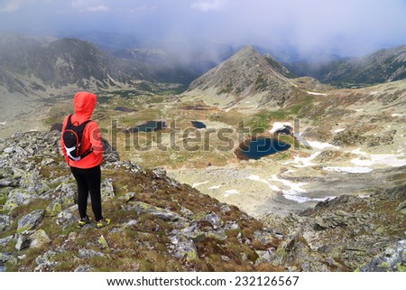 Young woman standing on the mountain trail above distant lake