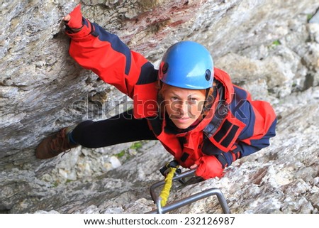 Narrow gap between rock walls and woman climber ascending on steel steps of via ferrata \