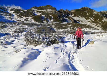 Winter hike with woman walking snow covered trail on the mountain