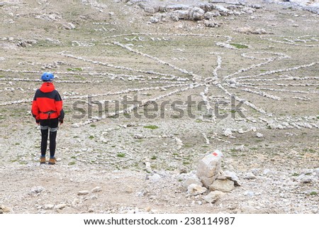 Woman climber and circular arrangement of rocks on the Meisules plateau, Sella massif, Dolomite Alps, Italy