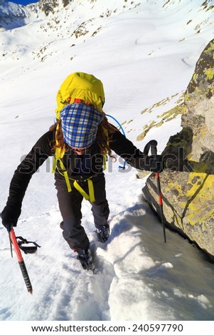 Mountain climber ascending a snowy trail with the help of the ice axe