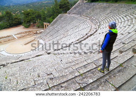 Visitor standing above ancient Greek amphitheater, Epidaurus, Greece