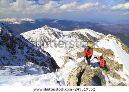 Sunny day on snow covered ridge and two climbers geared for winter climb