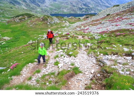 Mountain trail with small kid followed by his mother in overcast day