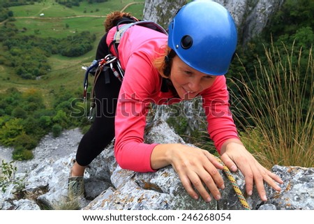 Woman climber holding on the limestone rock during climbing trip