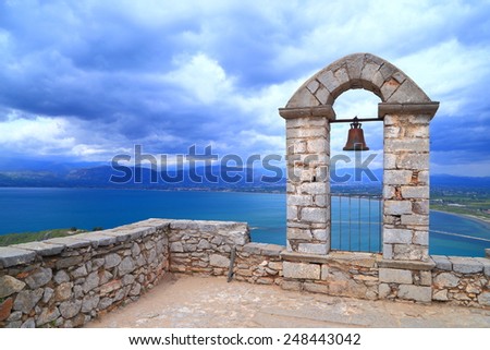 Stone walls of Palamidi fortress with small bell under menacing clouds, Nafplio, Greece