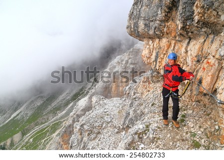 Climber walking along steep mountain side on via ferrata \