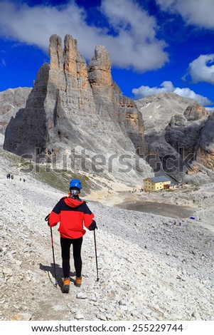 Woman climber approaching tall rocks of Vajolet towers, Catinaccio massif, Dolomite Alps, Italy