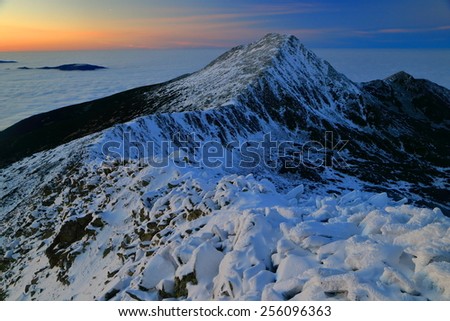 Snowy mountain range and distant valley at dusk in winter time