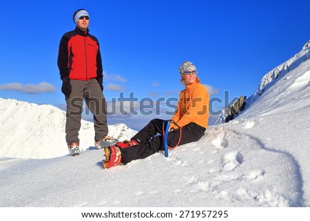 Mountain hikers resting on the snow during fine winter day