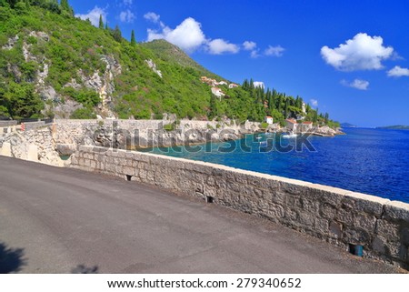 Adriatic sea shore with sunny road above the blue water in summer, Trsteno, Croatia