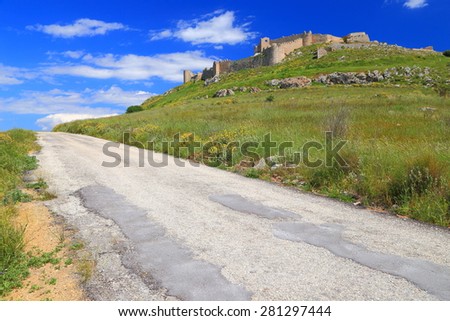 Sunny landscape with open road and medieval fortress of Larissa on a green hill, Argos, Greece