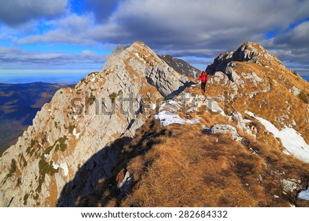 Sunny day of autumn on the mountain with remote backpacker isolated on aerial ridge