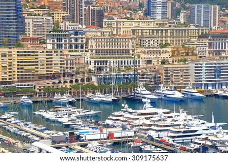 Luxury boats inside the main harbor of Monaco with luxury buildings and hotels of Monte Carlo in the background, Monaco