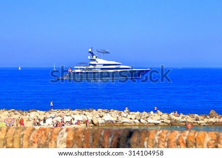 Helicopter landing on luxury yacht anchored outside Antibes harbor, French Riviera, France