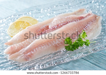 Fresh haddock fillets on glass plate with lemon and parsley. Stockfoto © 
