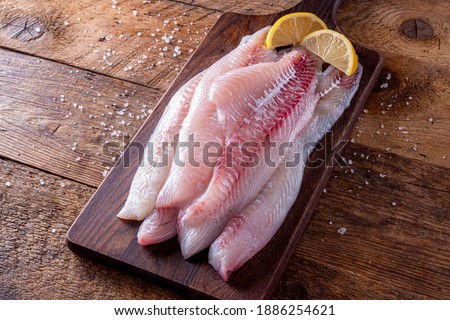 Fresh haddock fillets on a rustic table top with lemon wedges. Stockfoto © 
