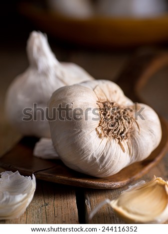 Garlic bulbs and cloves on a rustic wooden harvest table.