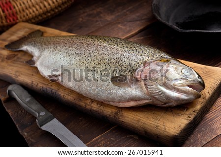 A rainbow trout on cutting board in a rustic cabin.