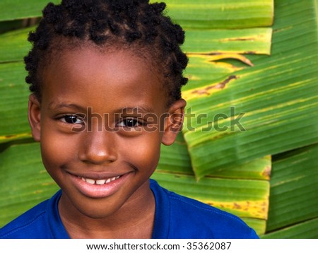 cute smiling boy with giant banana leaves in the caribbean