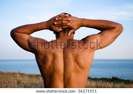 man in nature with hands behind head and back showing