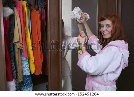 woman cleaning furniture cabinet with yellow duster