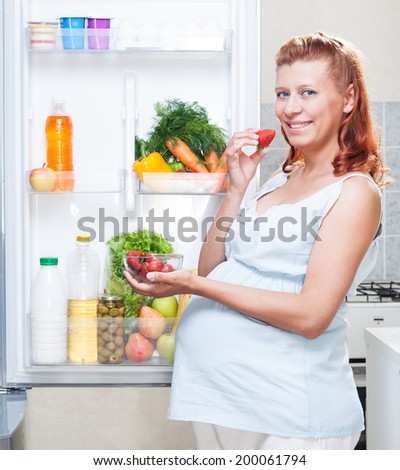 pregnant woman and refrigerator with health food vegetables and fruits