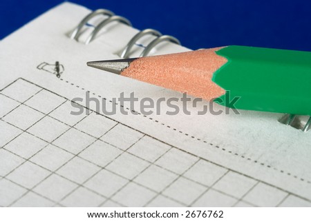green pencil and notebook on blue background