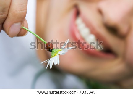 close-up smiling woman holding flower camomile with ladybug outdoor