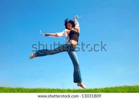 happy woman jump in field under blue sky and clouds
