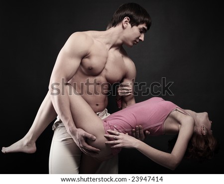 strong man hold delicate girl on black background