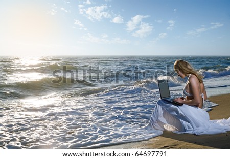 blond girl using laptop on  sea beach