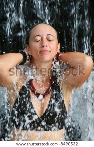 A young woman under a hot spring waterfall in Costa Rica