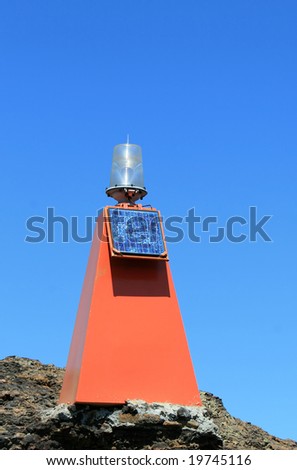 A bright orange beacon with solar panel warns ships of rocks and aids navigation
