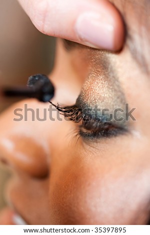 A young Indian woman has eye make-up applied at a salon
