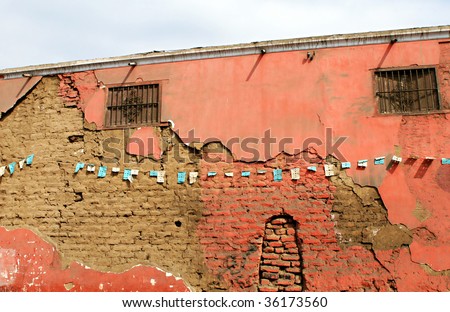 Plaster work falling off of a brick wall in the city of Trujillo, Peru